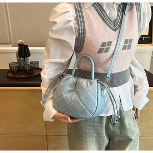 Detail of light blue quilted leather handbag with side drawstring and adjustable strap