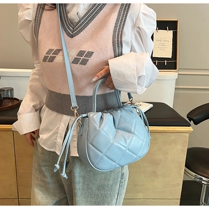 Detail of light blue quilted bucket bag with drawstring closure and fine stitching textures
