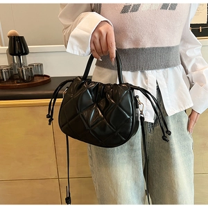 Detail of black quilted bucket bag with drawstring closure and fine leather texture