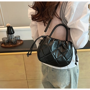 Detail of black quilted cloud bag showing diamond stitching and adjustable strap