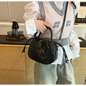 Detail of black quilted PU leather crossbody bag with drawstring and top handle