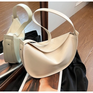 Detail of a creamy beige crescent tote bag featuring soft faux leather and a wide strap