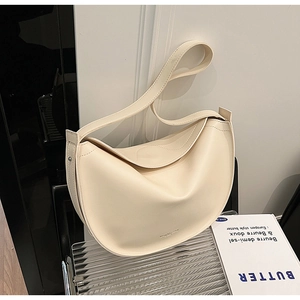Detailed view of cream hobo bag made of smooth faux leather with a minimalist logo