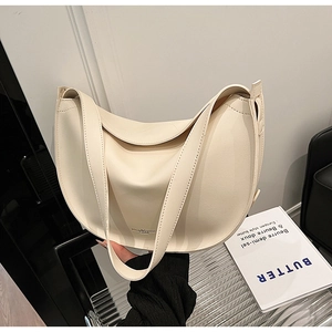 Detailed view of the ivory crescent tote bag with branding on the lower matte leather surface