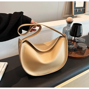 Detailed close-up of a beige crescent hobo bag with gold logo on a textured leather finish