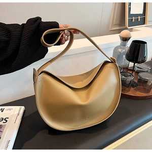 Close-up of minimalist khaki crescent bag with slim shoulder strap in a home setting