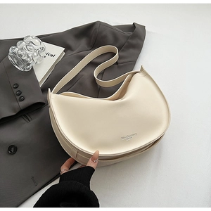 Minimalist beige half-moon tote bag displayed with a blazer for a chic office look