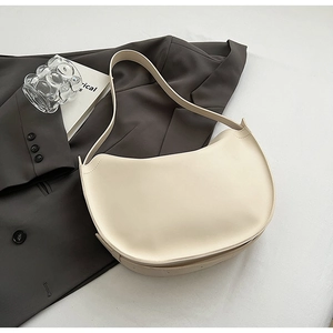 Detail of the cream-colored crescent hobo bag featuring smooth faux leather and wide strap