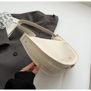 Detail of off-white crescent tote bag with metal rivets on grey blazer background