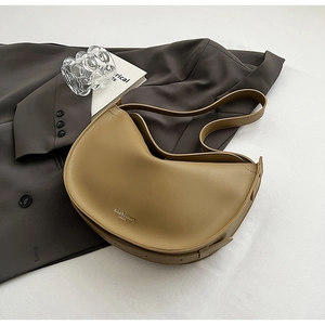 Macro detail of khaki leather hobo bag with gold logo on a stylish textured background