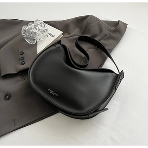 Detail of black crescent shoulder bag featuring silver logo and adjustable wide strap