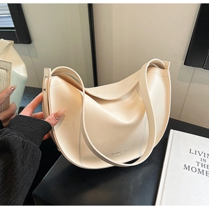 Detailed close-up of cream curved shoulder bag with brand logo and smooth texture