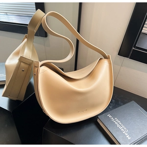 Detail shot of a minimalist beige hobo bag with a smooth leather finish and wide strap