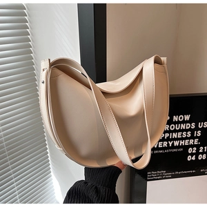 Detail of minimalist cream crescent hobo bag with wide shoulder strap in natural light