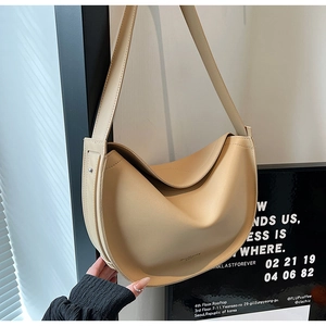 Detail of adjustable buckle and matte PU leather texture on a beige crescent tote bag