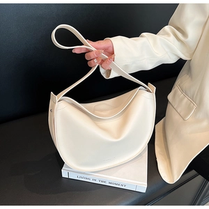 Detail of a minimalist cream hobo bag on a book with soft leather texture and stylish drapes