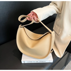Detail of minimalist beige faux leather hobo bag with wide shoulder strap and curved shape
