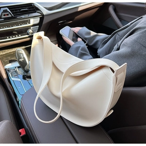 Chic beige crescent tote bag placed on a car passenger seat for an urban lifestyle view