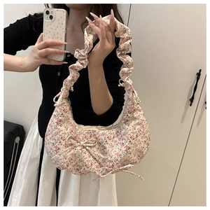 Detail view of floral canvas bag featuring ruched shoulder straps and bow accents