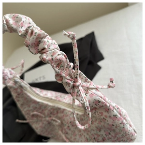 Détail du sac en toile fleurie avec une anse froissée et un nœud décoratif assorti