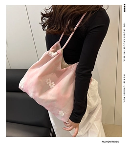 Gros plan d'un sac cabas en maille rose avec broderies de fleurs 3D et anses