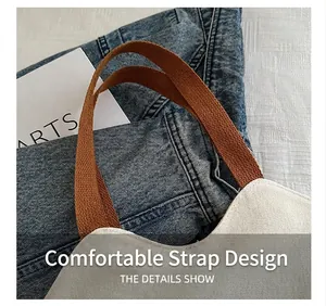Detail of cream canvas tote bag showing brown textured strap with reinforced stitching