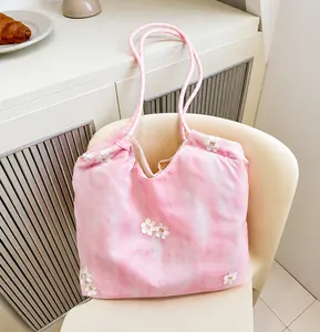 Detail of pink tie-dye tote bag with floral embroidery hanging on a chair