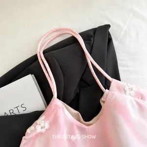 Close-up of pink fabric tote bag featuring white floral embroidery and thin handles