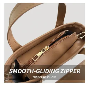 Close-up of smooth gold metal zipper and stitching on brown leather bucket bag