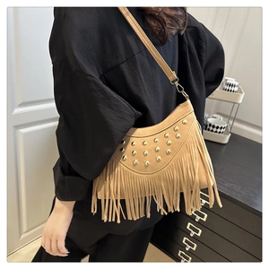 Close-up of vintage brown suede shoulder bag with golden studs and bohemian fringe detail