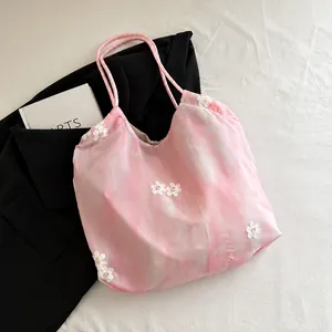 Close-up of pink marble tote bag with white floral embroidery and thin shoulder straps