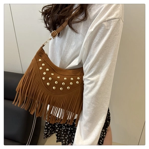 Detail of bohemian saddle bag with gold rivets and long fringe hanging from the base