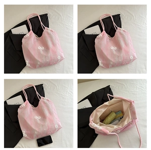 Detail van bloemenborduurwerk op roze tie-dye tas met focus op de binnenruimte