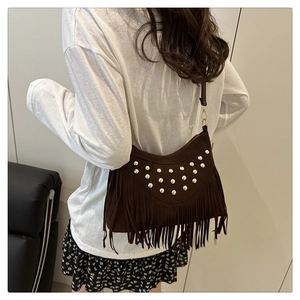 Detail of dark brown suede crossbody bag with fringe tassels and gold metallic studs