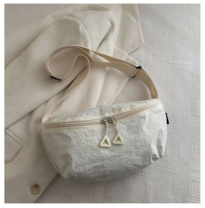 Détail du sac croissant en nylon crème montrant la texture plissée et double zip