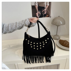 Detail of black suede bag featuring gold rivet studs and long fringe tassels