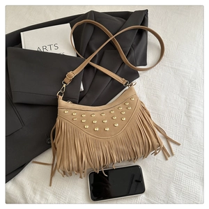 Close-up of khaki suede crossbody bag featuring gold studs and long stylish fringes