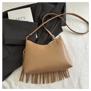 Close-up of light brown faux leather handbag with dense fringe tassels and adjustable strap