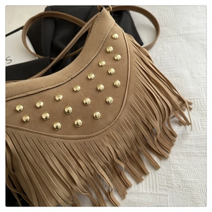 Close-up of brown suede moon bag with gold rivets and long fringe tassel detail