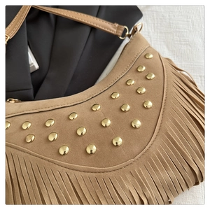 Detail of brown suede crescent bag with gold studs and long fringe tassels