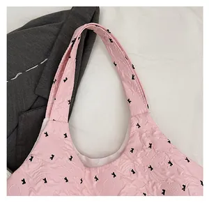 Detail of pink tote bag with embossed black bear patterns and soft fabric texture