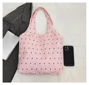 Pink quilted tote bag with rabbit print detail showing capacity against a gray blazer