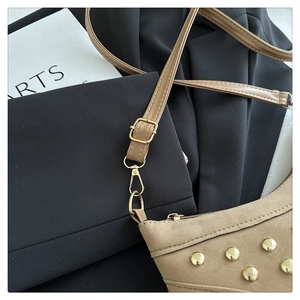 Detailed close-up of beige suede crossbody bag featuring gold studs and hardware