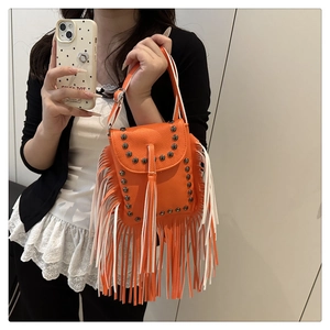 Detalle de bolso boho naranja con flecos, remaches metálicos y acabado de piel rugosa