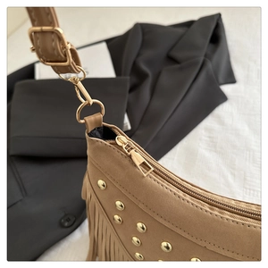 Close-up of golden zipper and rivet details on bohemian khaki tassel shoulder bag