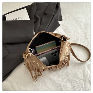 Interior view of brown suede crossbody bag with rivets and tassels showing storage capacity