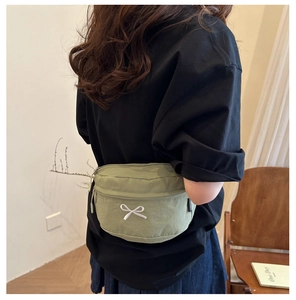 Dettaglio del marsupio verde chiaro con elegante ricamo a fiocco bianco