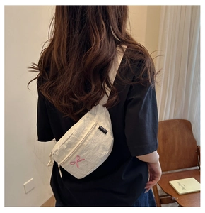 Gros plan sur le sac croissant crème avec broderie nœud rose et bandoulière large