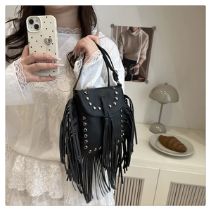 Detalle del bolso bandolera de cuero negro con flecos largos y remaches plateados