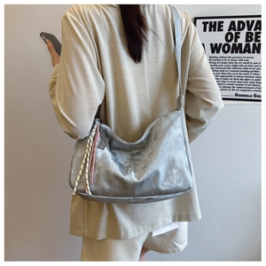 Dettaglio della borsa hobo argento metallizzato con nappa rosa e ciondolo a spalla